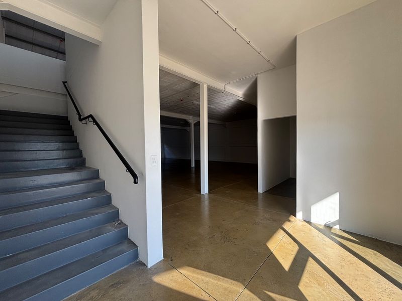 Spacious open-plan industrial interior featuring polished concrete floors, a staircase with a metal handrail, and exposed structural elements.