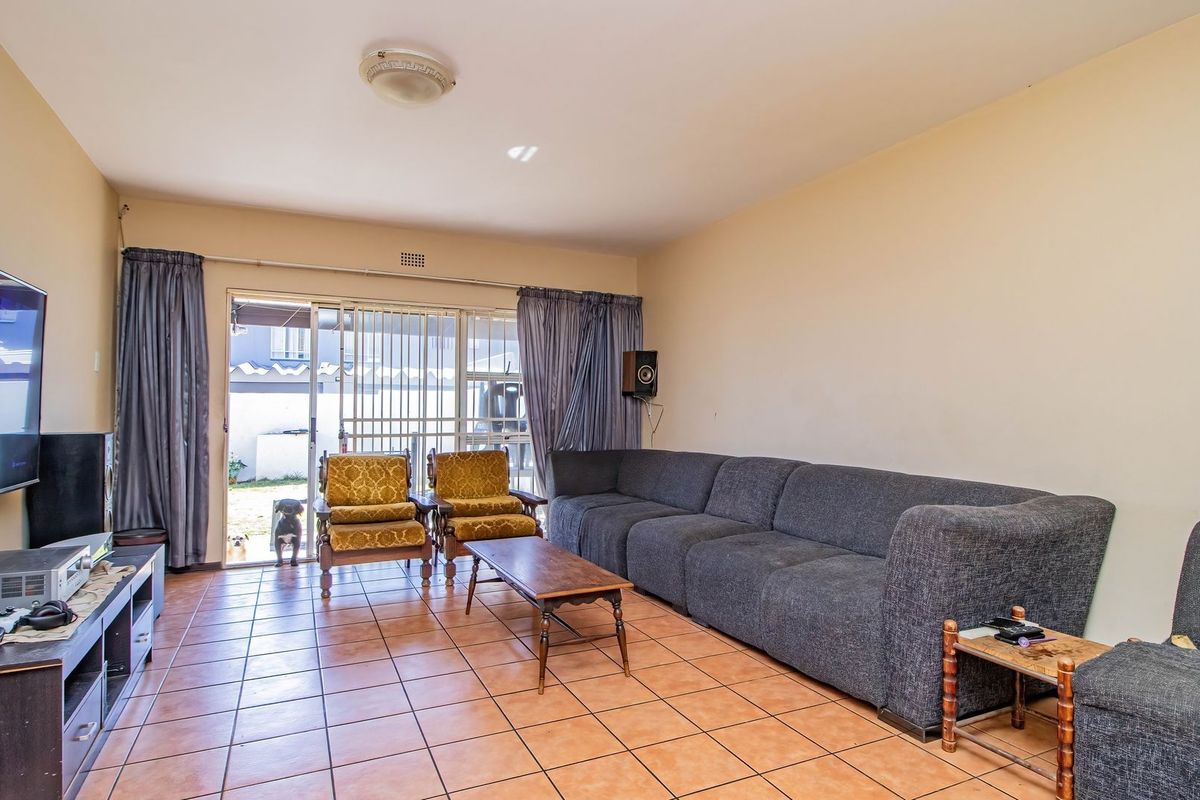 A spacious living room featuring tiled flooring and a sliding glass door that provides access to the outdoor area.