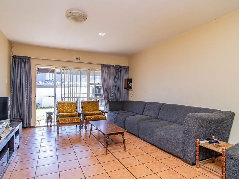 A spacious living room featuring tiled flooring and a sliding glass door that provides access to the outdoor area.