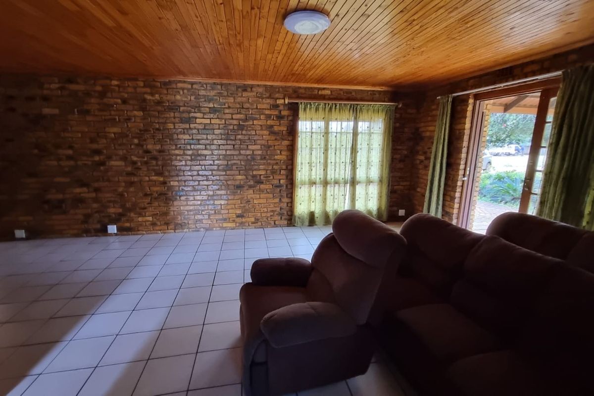 Spacious living area featuring exposed brick walls, tiled flooring, and a timber-clad ceiling with direct access to the outdoor patio.