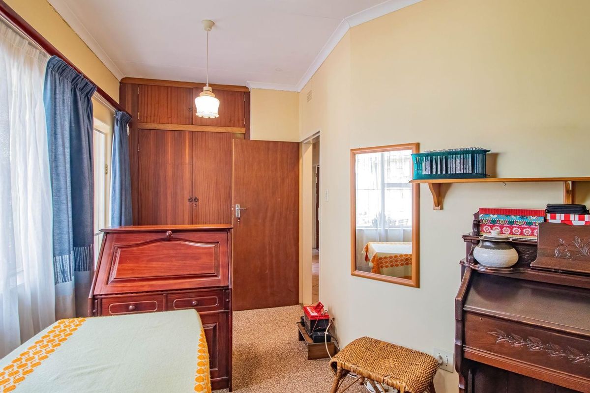 A bedroom featuring built-in wooden cupboards, carpeted flooring, and a window with natural light.