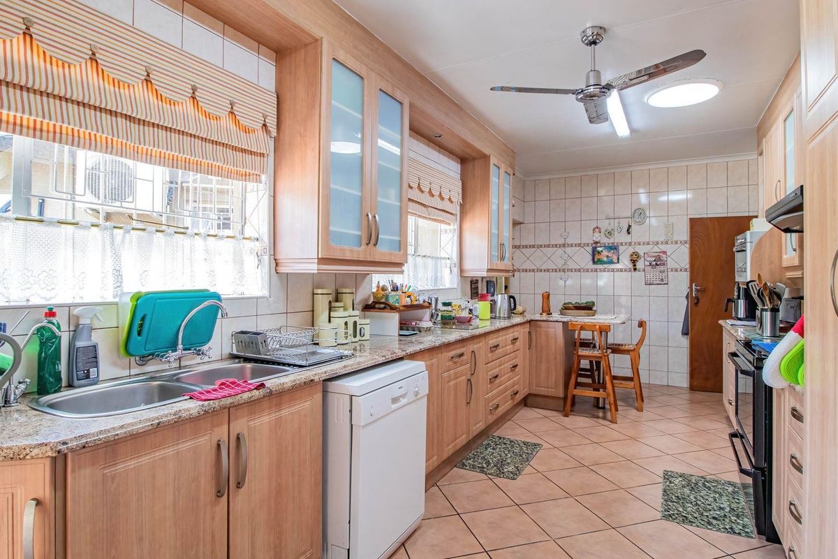 A functional kitchen featuring light wood cabinetry, granite countertops, tiled flooring, and a built-in oven with an extractor fan.