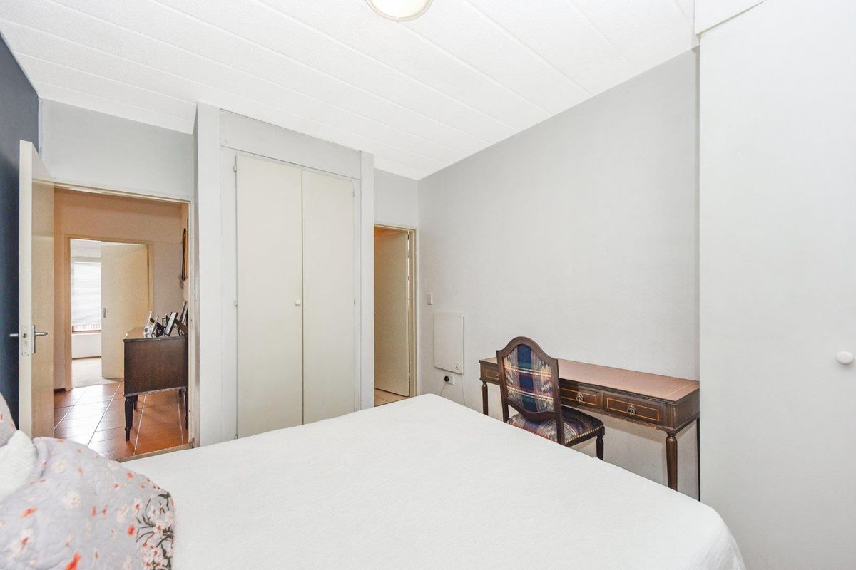 A bedroom featuring built-in cupboards and access to an adjoining hallway, finished with neutral walls and a textured ceiling.
