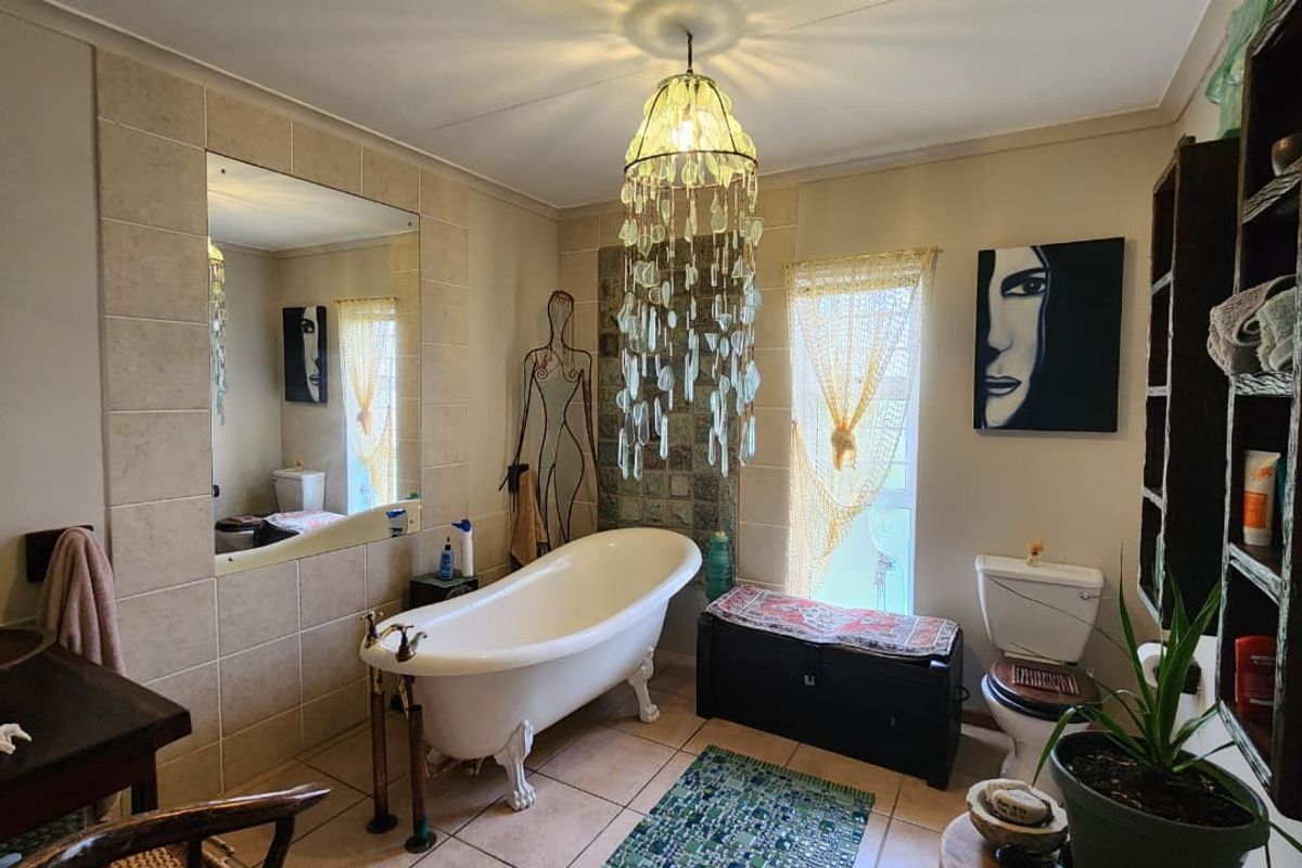 A characterful bathroom featuring a classic clawfoot bathtub, large wall-mounted mirror, and tiled flooring, offering a unique and vintage-inspired aesthetic.