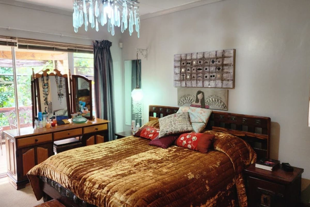 A spacious bedroom featuring a large window with direct access to an outdoor patio area, providing natural light and a view of the garden.