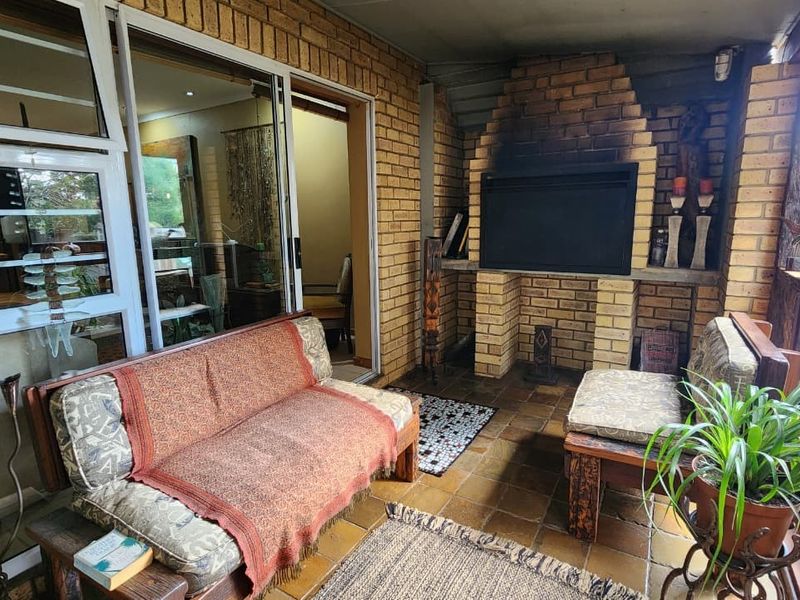 Covered patio area featuring a built-in brick fireplace, tiled flooring, and sliding glass door access to the interior living space.