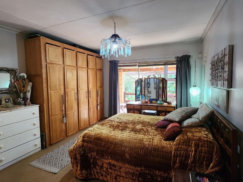 Spacious bedroom featuring extensive built-in wooden cabinetry, neutral carpeting, and direct access to an outdoor patio area.
