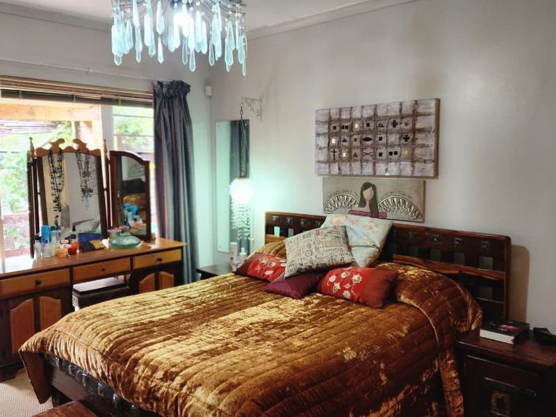A spacious bedroom featuring a large window with direct access to an outdoor patio area, providing natural light and a view of the garden.