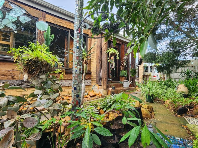 A rustic exterior view of the home featuring timber-framed windows, brickwork, and a landscaped garden path leading to the entrance.