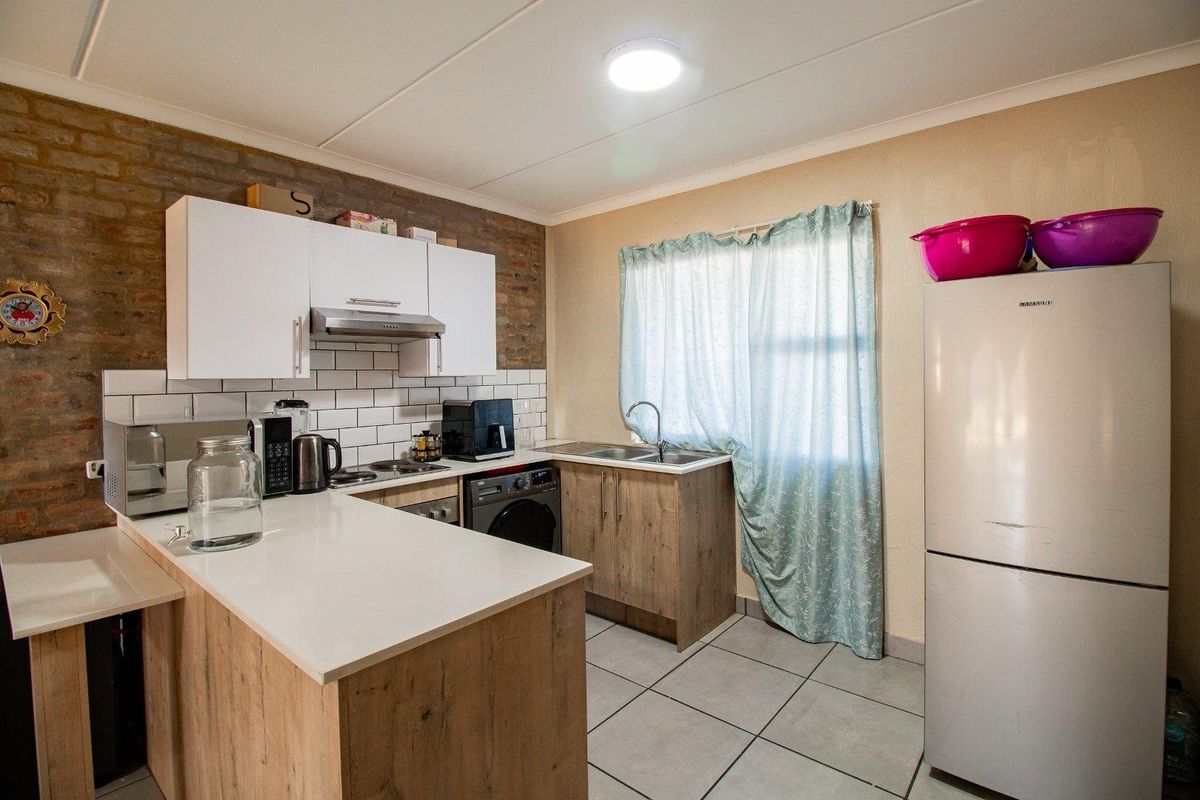 Compact kitchen featuring a breakfast bar, white subway tile backsplash, modern cabinetry, and integrated sink area with tiled flooring.