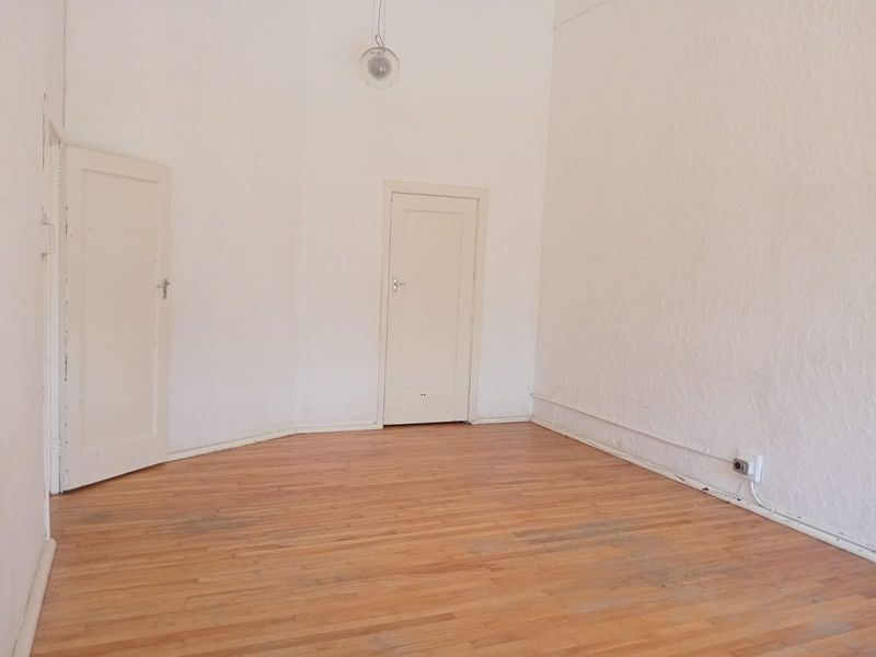 An empty bedroom featuring original timber flooring, white walls, and two internal doors, offering a blank canvas for renovation or interior design.