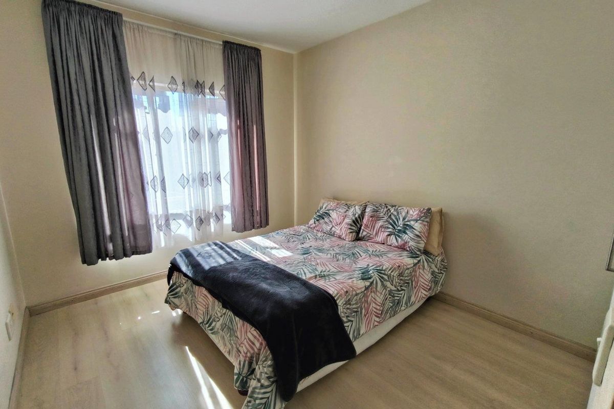 A well-lit bedroom featuring light-toned laminate flooring and neutral wall finishes, providing a clean and functional space.