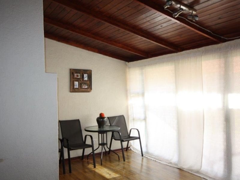 A covered patio area featuring a warm timber ceiling, wooden flooring, and large sliding glass doors that provide ample natural light.