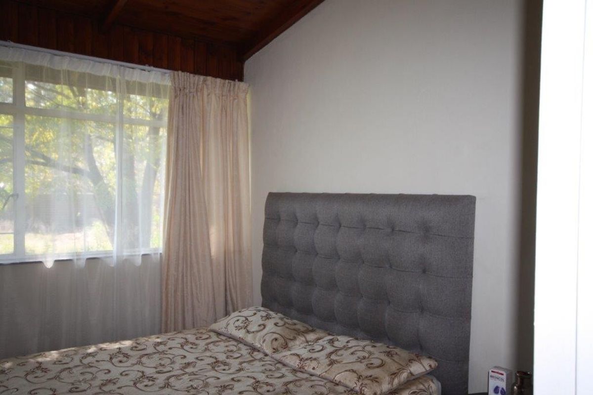 A bedroom featuring a timber-paneled ceiling and a large window that allows for natural light.