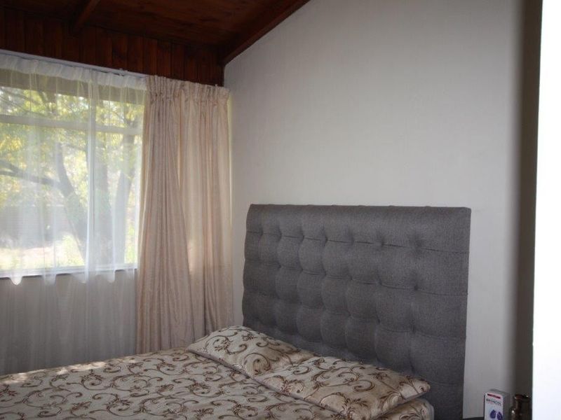 A bedroom featuring a timber-paneled ceiling and a large window that allows for natural light.