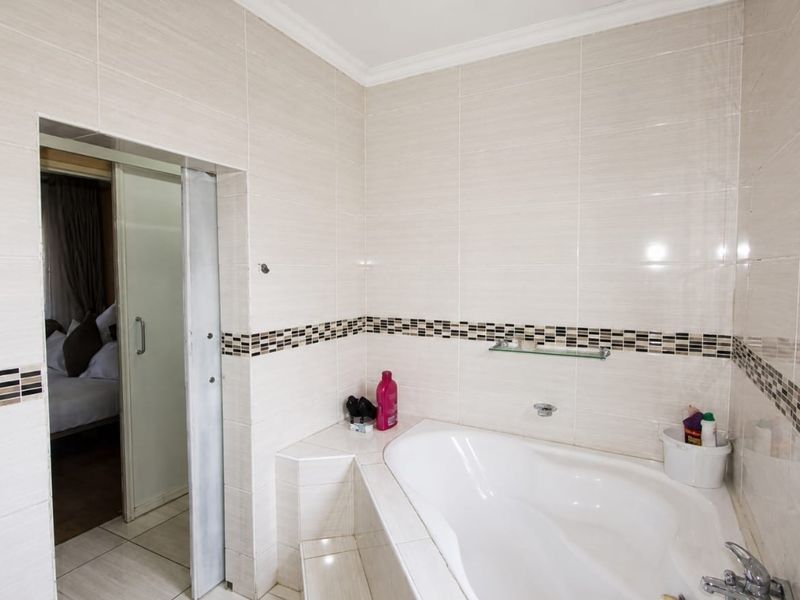 A clean bathroom featuring a built-in bathtub with tiled surround and walls, complemented by a sliding door entrance.