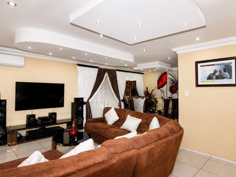 Spacious living room featuring a modern recessed ceiling with integrated downlights, tiled flooring, and a wall-mounted air conditioning unit.