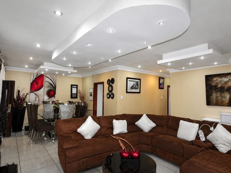 Spacious open-plan living and dining area featuring a modern recessed ceiling with integrated downlights and polished tiled flooring throughout.