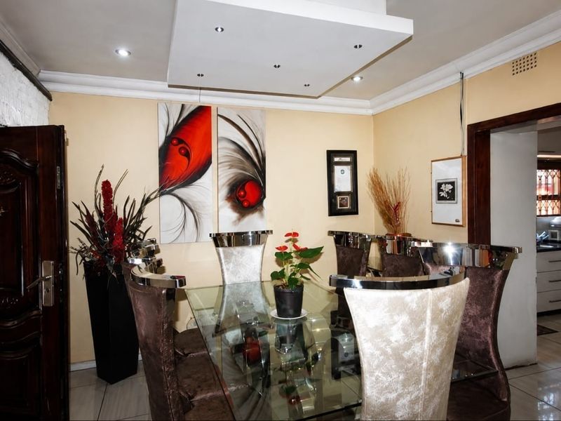 A dining room featuring a recessed ceiling with downlights, tiled flooring, and coved cornice, providing a functional space for formal meals.