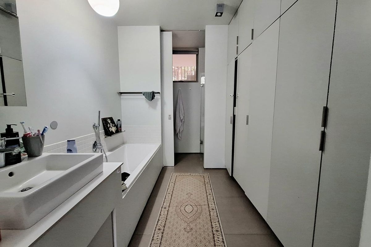 Modern bathroom featuring a built-in bathtub, integrated vanity sink, and extensive floor-to-ceiling white cabinetry providing ample storage space.