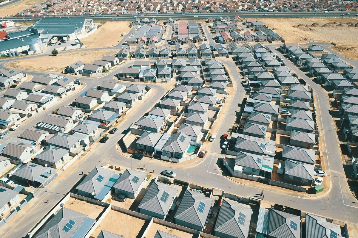 An aerial view of a modern residential housing estate featuring uniform detached homes with tiled roofs and solar panels.
