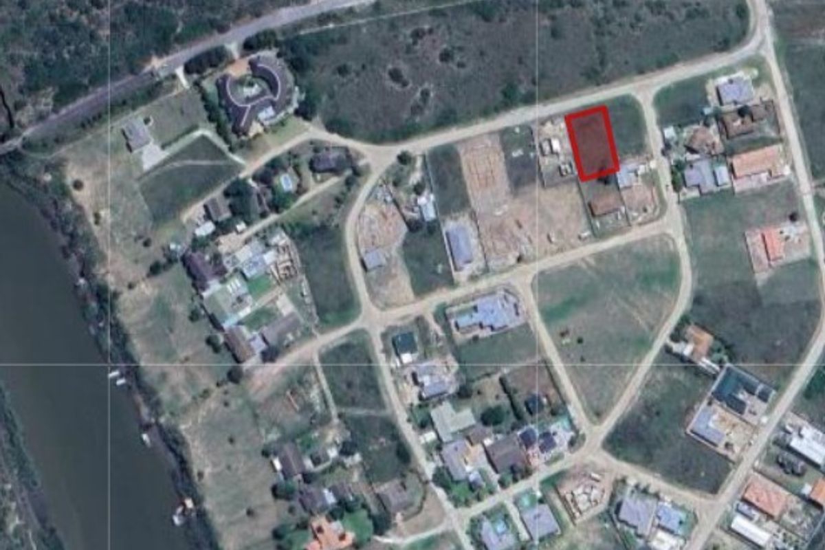 An aerial view of a vacant residential land plot highlighted in red within a developed estate setting.