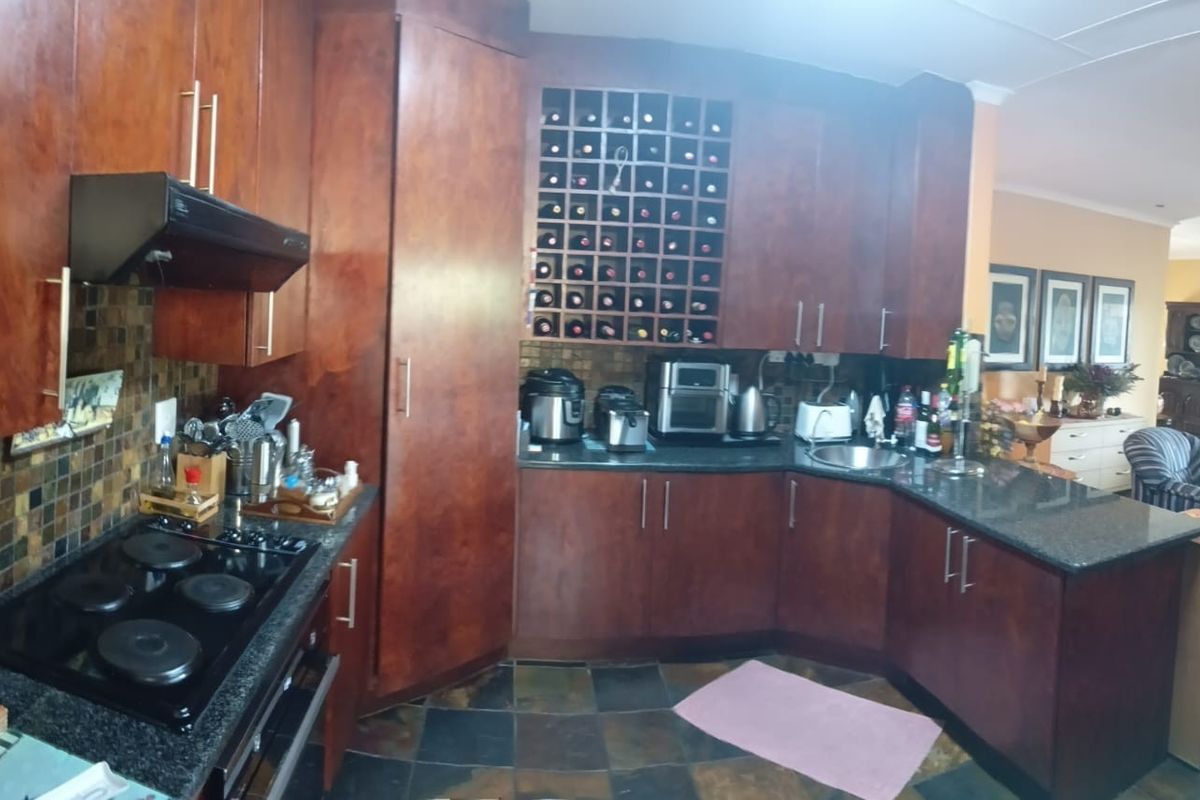 A functional kitchen featuring dark wood cabinetry, granite countertops, a built-in wine rack, and slate tile flooring, seamlessly flowing into the adjacent living area.