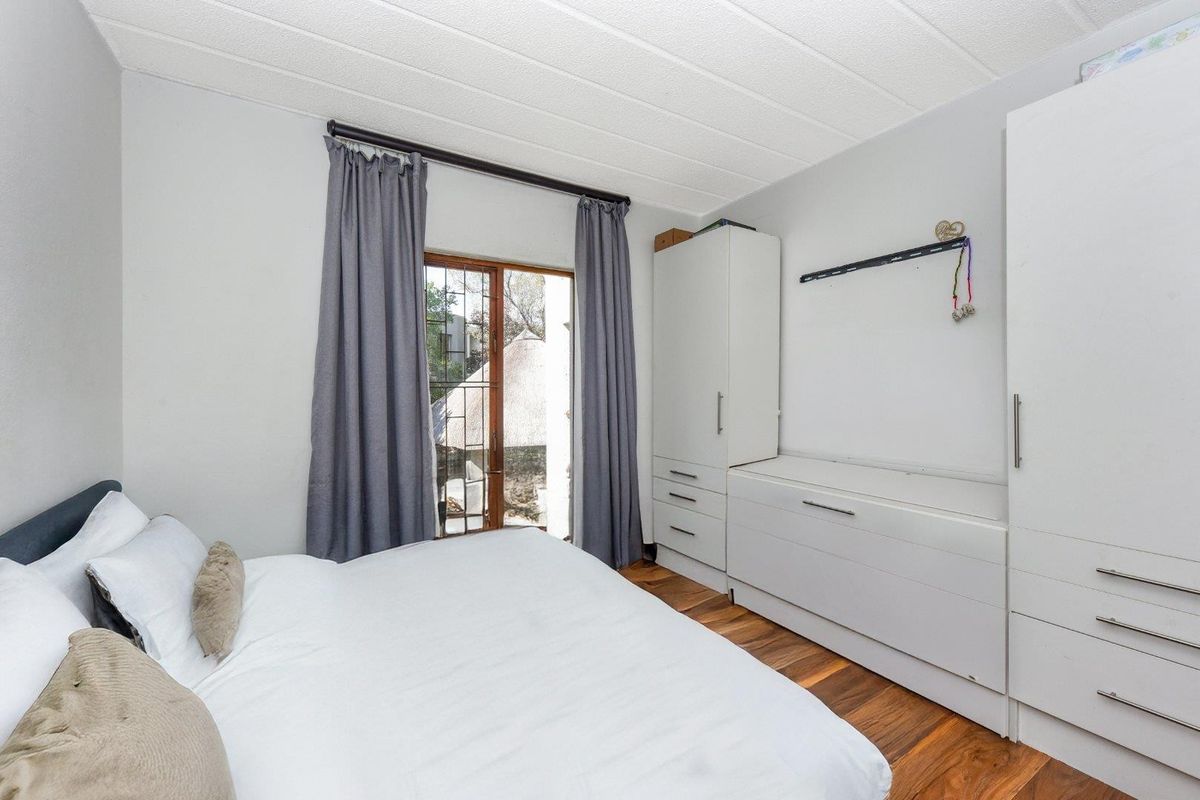 A bedroom featuring built-in white cabinetry, wood-look flooring, and a sliding door providing access to an outdoor area.