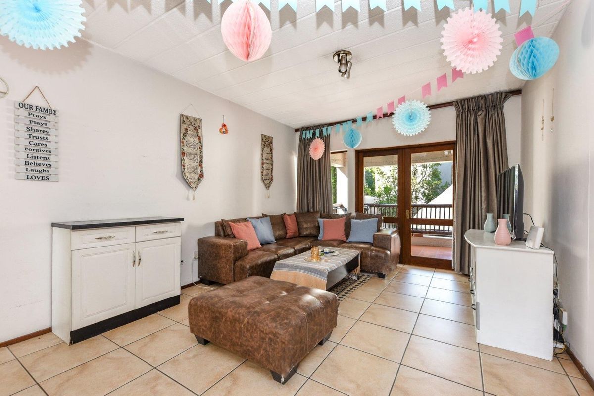 Spacious living room featuring neutral floor tiles and direct access to a private balcony through sliding glass doors.