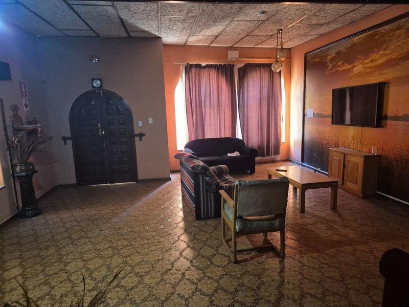 Spacious living room featuring an arched double door entrance, textured ceiling tiles, and patterned vinyl flooring, offering a dated aesthetic ready for modernization.