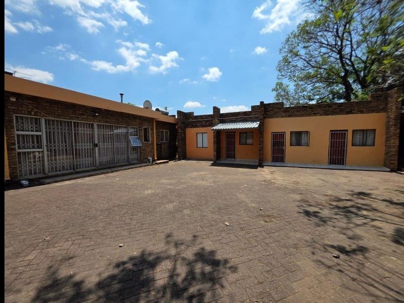A spacious paved rear courtyard area featuring brick exterior walls and multiple access points with security gates.