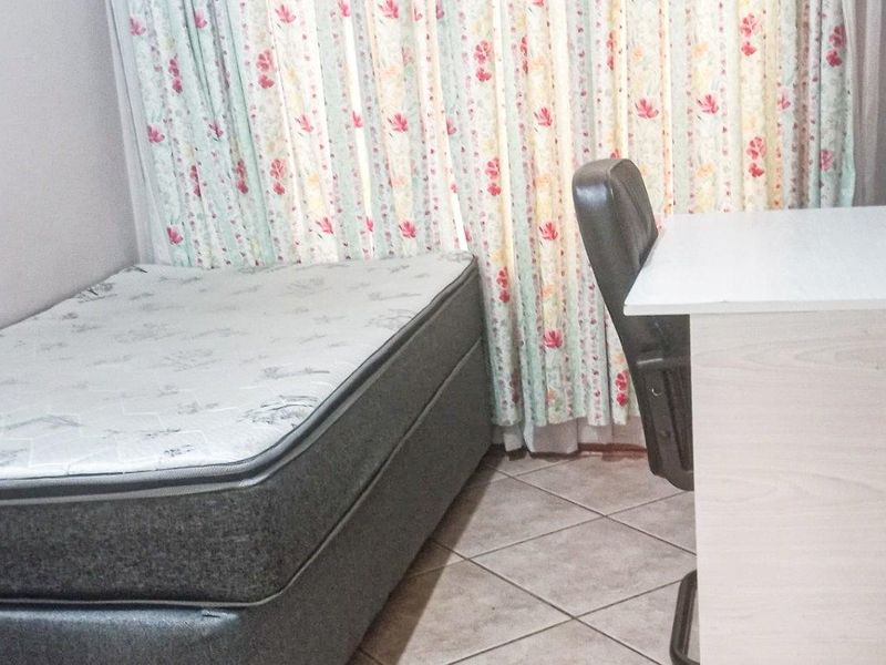 A functional bedroom featuring tiled flooring and window treatments.