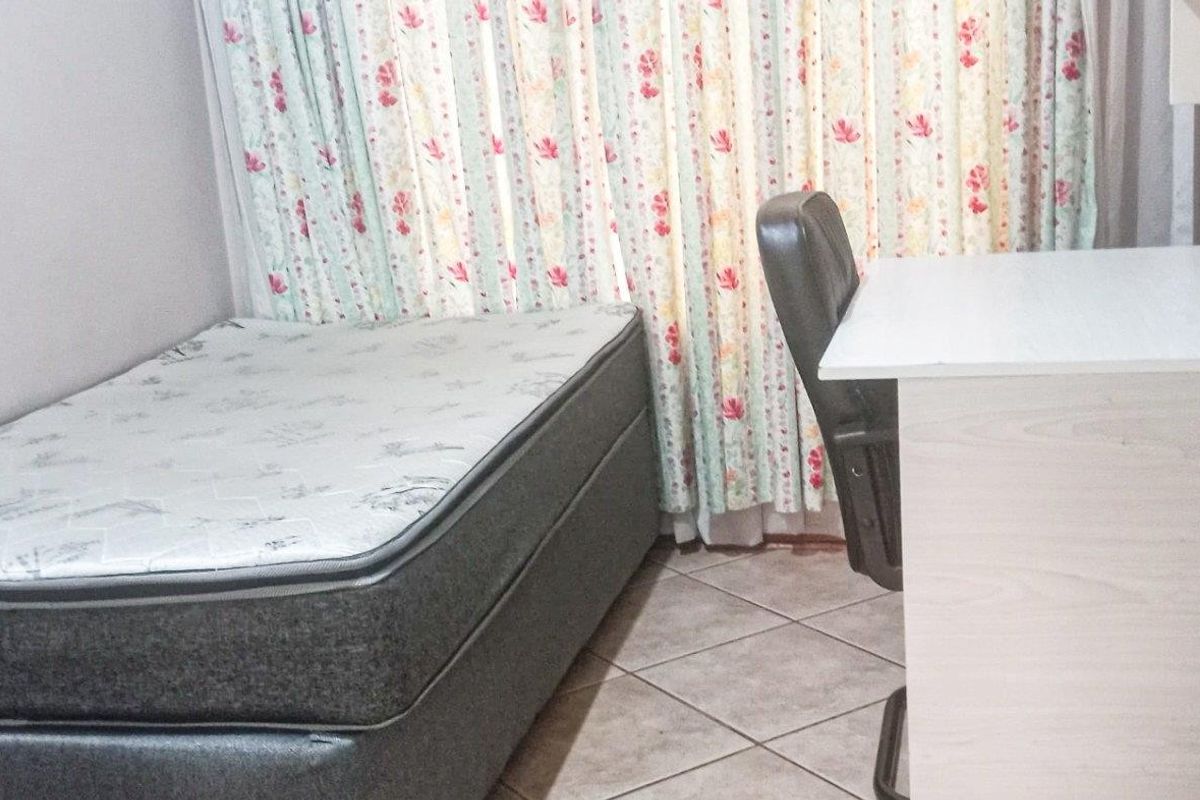 A functional bedroom featuring tiled flooring and window treatments.