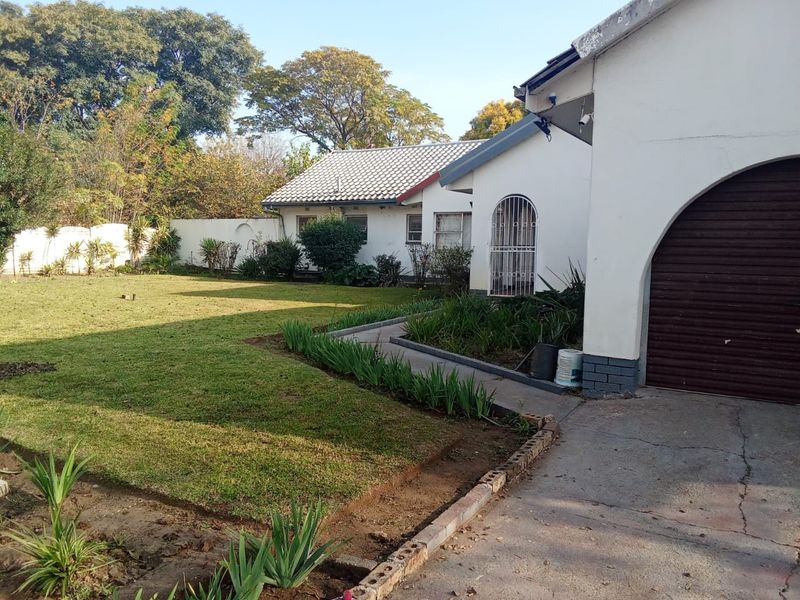 Front view of the property featuring a lawn, concrete driveway, and garage access with a secure entrance.