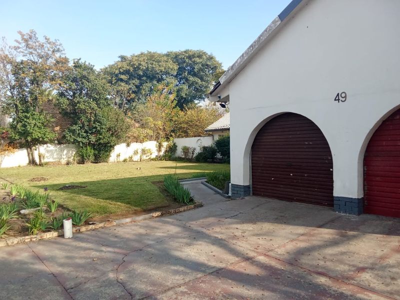 Front view of the property featuring a double garage with arched openings, a concrete driveway, and a spacious front garden area.