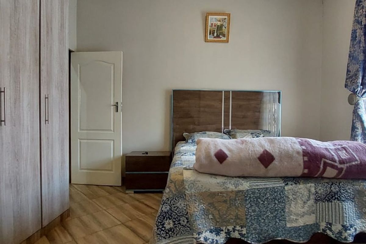 A well-maintained bedroom featuring built-in wooden cabinetry, tiled flooring, and a window with natural light.