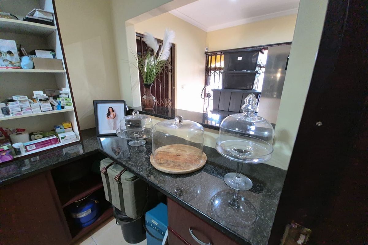 A functional kitchen serving area featuring dark granite countertops, built-in cabinetry, and an open-plan layout connecting to the adjacent living space.