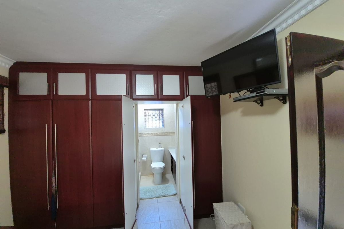 Bedroom featuring extensive built-in dark wood cabinetry with overhead storage and an integrated en-suite bathroom with tiled flooring.