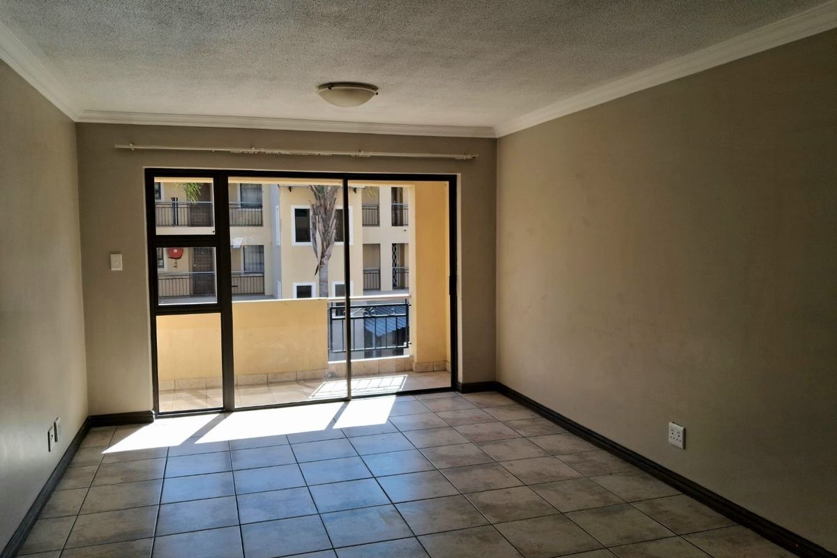 An empty living room featuring tiled flooring and a large sliding glass door providing access to an outdoor balcony area.