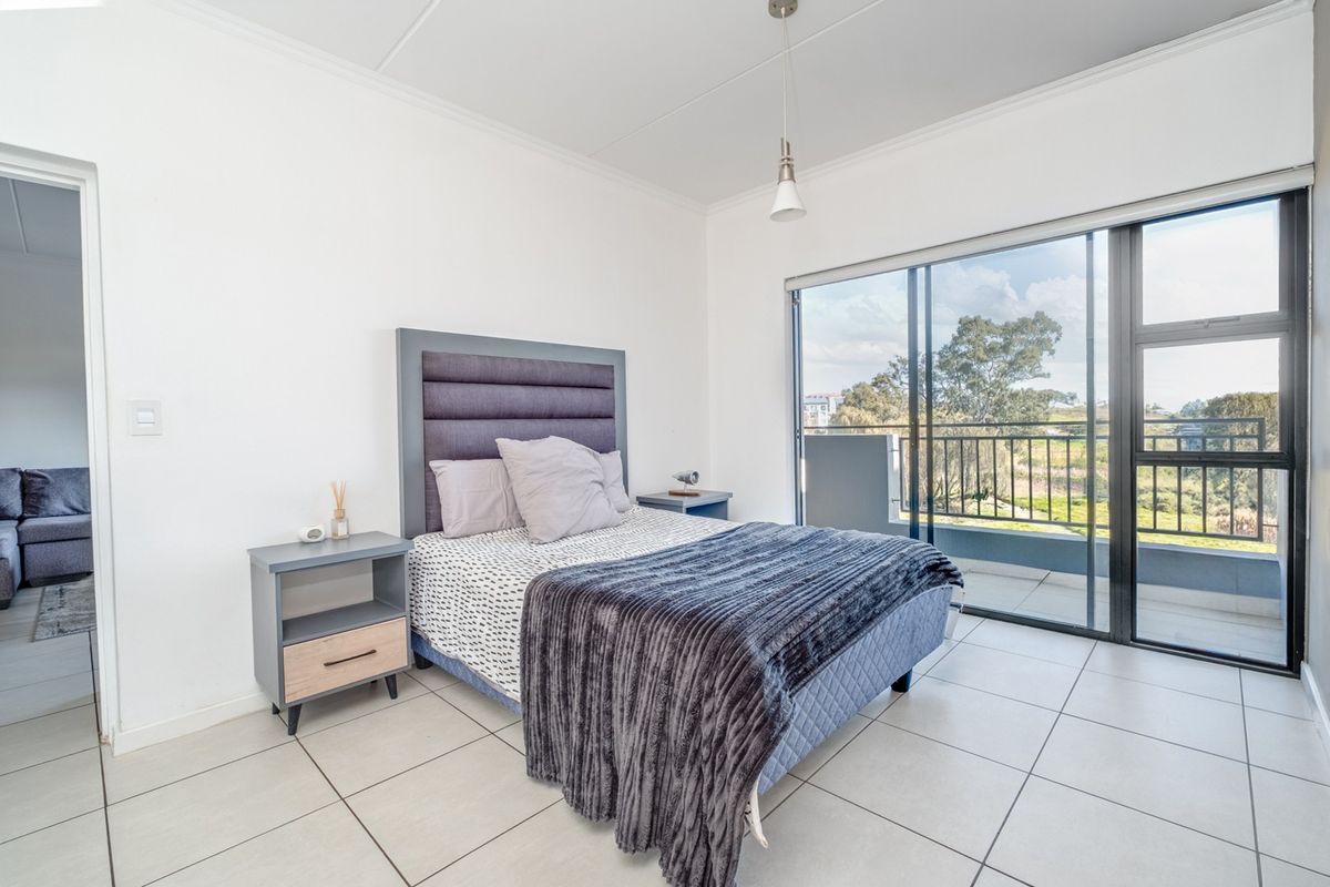 Bright bedroom featuring large sliding glass doors that open onto a private balcony, offering natural light and scenic views.