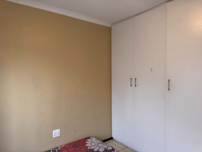 A bedroom featuring built-in cupboards and neutral wall finishes, offering a functional space ready for personalization.