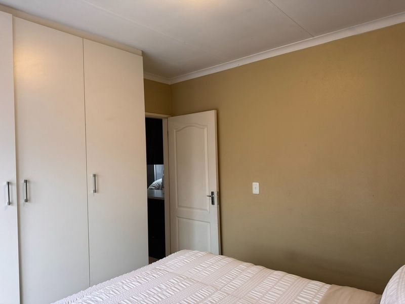 A bedroom featuring a built-in wardrobe with white cabinetry and a neutral wall finish.