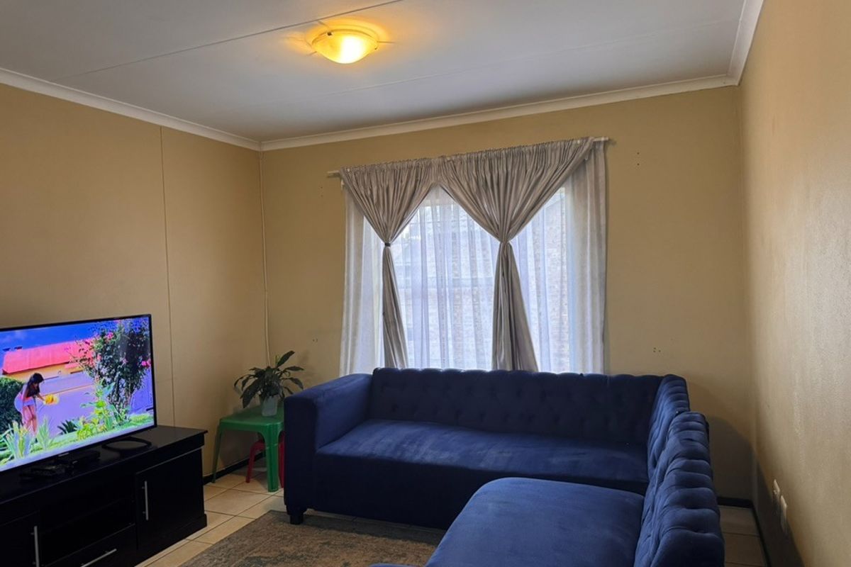 A functional living room featuring tiled flooring and neutral wall finishes, providing a comfortable space for relaxation.