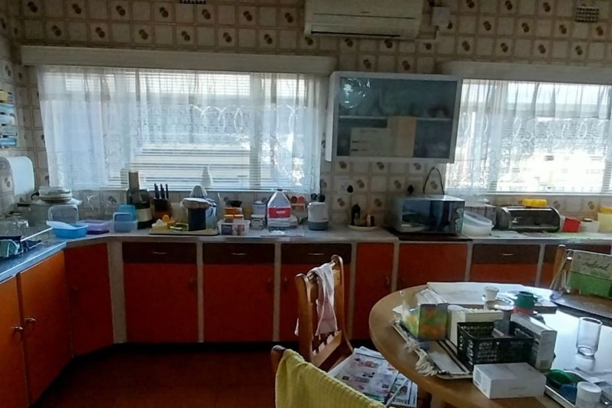 A dated kitchen featuring orange cabinetry, tiled walls, and a double sink, offering a functional layout with significant potential for modernization.