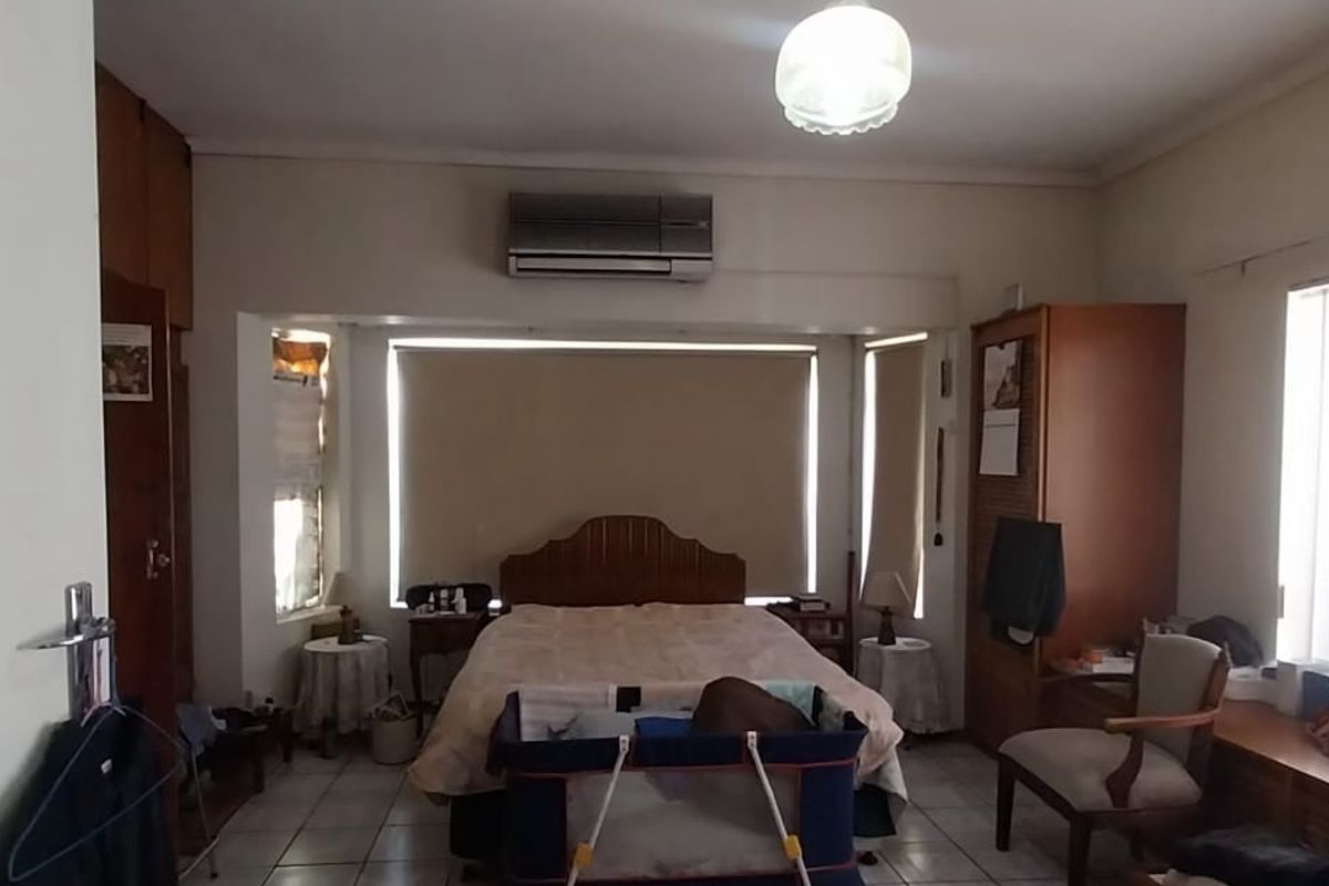 A spacious bedroom featuring tiled flooring, built-in cabinetry, and a wall-mounted air conditioning unit.