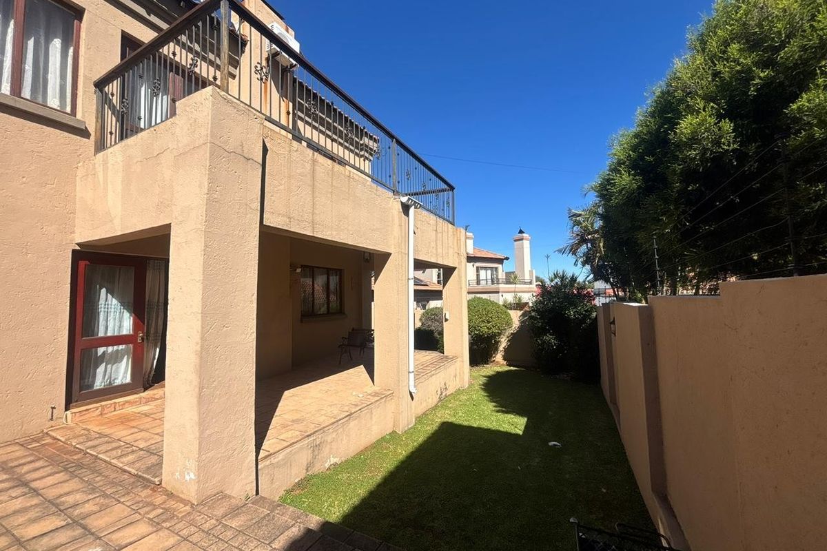 Rear view of the property featuring a covered patio, an upper-level balcony with metal railings, and a private garden area.