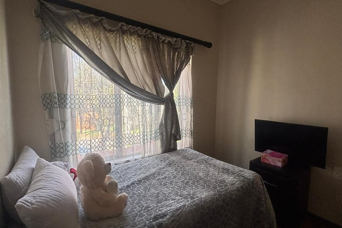A cozy bedroom featuring a window with curtain rod and neutral wall finishes.