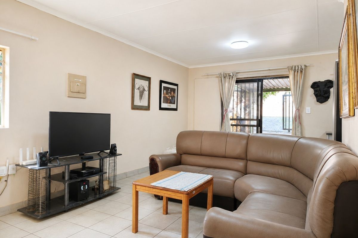 A functional living room featuring tiled flooring and a sliding glass door providing access to the outdoor area.