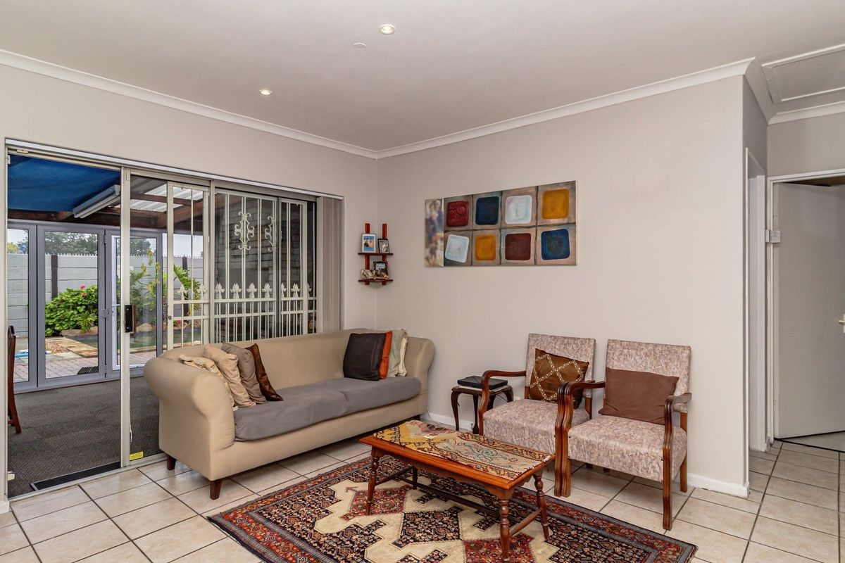 A living room featuring tiled flooring, recessed ceiling lighting, and large sliding glass doors providing access to an outdoor patio area.