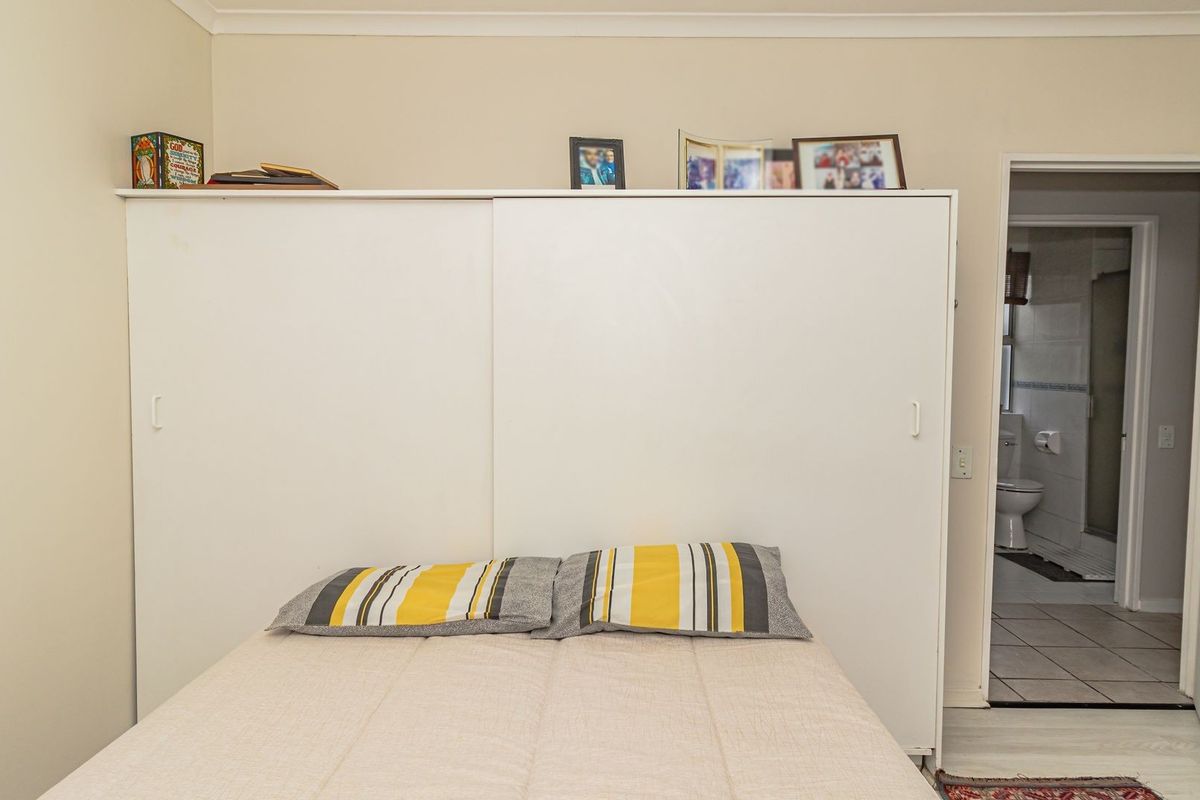 A bedroom featuring a large built-in sliding door wardrobe and direct access to an en-suite bathroom with tiled flooring.
